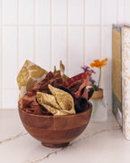 Wooden bowl with a set of patterned cotton cloths on a marble kitchen surface