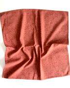 Slightly crumpled geometric red-orange cotton napkin on a white background